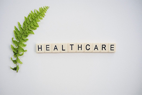 Letter tiles form the word "healthcare," while a lively plant symbolizes growth nearby.