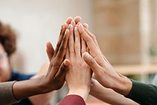 Several hands unite, standing together in a gesture of solidarity.