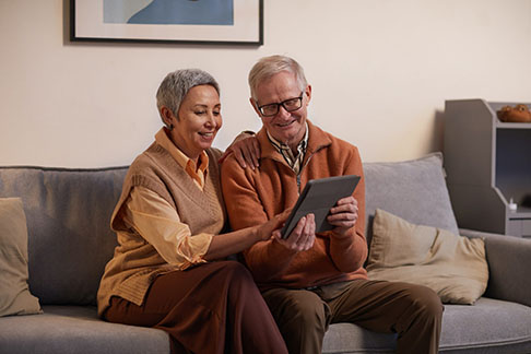 A senior woman and man sit together, happily viewing the Enduring Power of Attorney document on a screen.