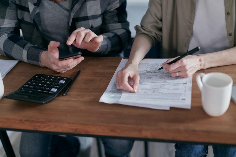 A woman and a man in front of a table with tax papers.